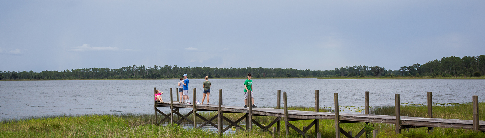 Youth sitting on a dock on a lake at 4-H Camp Ocala.