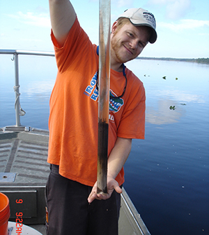 photo of a young male volunteer holding a pipe to take a sample of water