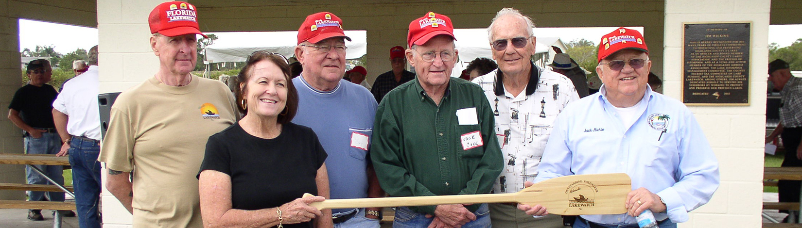 Photo of a group of volunteers holding a commemorative paddle