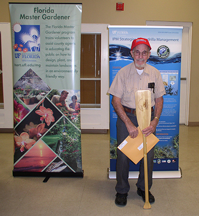 photo of volunteer Jack Neal holding an Outstanding Volunteer paddle